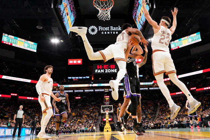 Nov 17, 2023; San Antonio, Texas, USA; Sacramento Kings center Domantas Sabonis (10) gets crushed by San Antonio Spurs forward Julian Champagnie (30) and center Zach Collins (23) during the second half at Frost Bank Center.